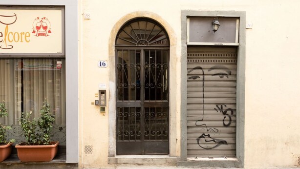 Ein Gebäude mit einer Schaufensterfront mit der Aufschrift „El core“ und einer verschlossenen Metalldür mit einem darauf gezeichneten Gesicht.
