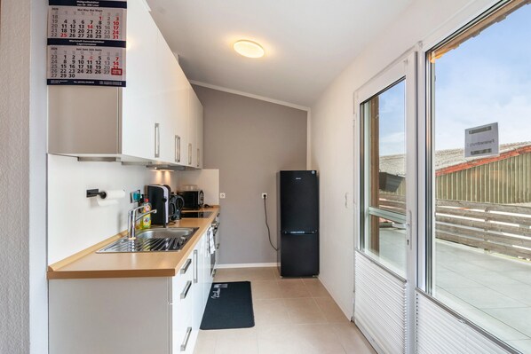 A compact kitchenette with a refrigerator, microwave, and sink. - Apartment 'Ferienwohnung 2' in Northeim – Komfort für 2 Gäste (Northeim)