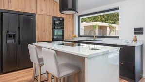 Una cocina moderna con una isla central, electrodomésticos de acero inoxidable y un ventanal grande.