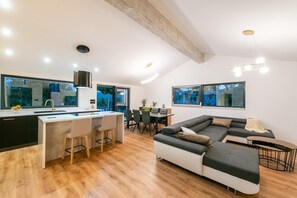 A modern kitchen with a dining area, a large sofa, and a small table. - Relaxed Family Villa with Private Pool (Naklice)