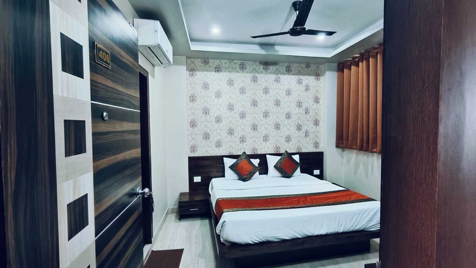 A bedroom with a bed, a ceiling fan, an air conditioning unit, and a patterned wallpaper.