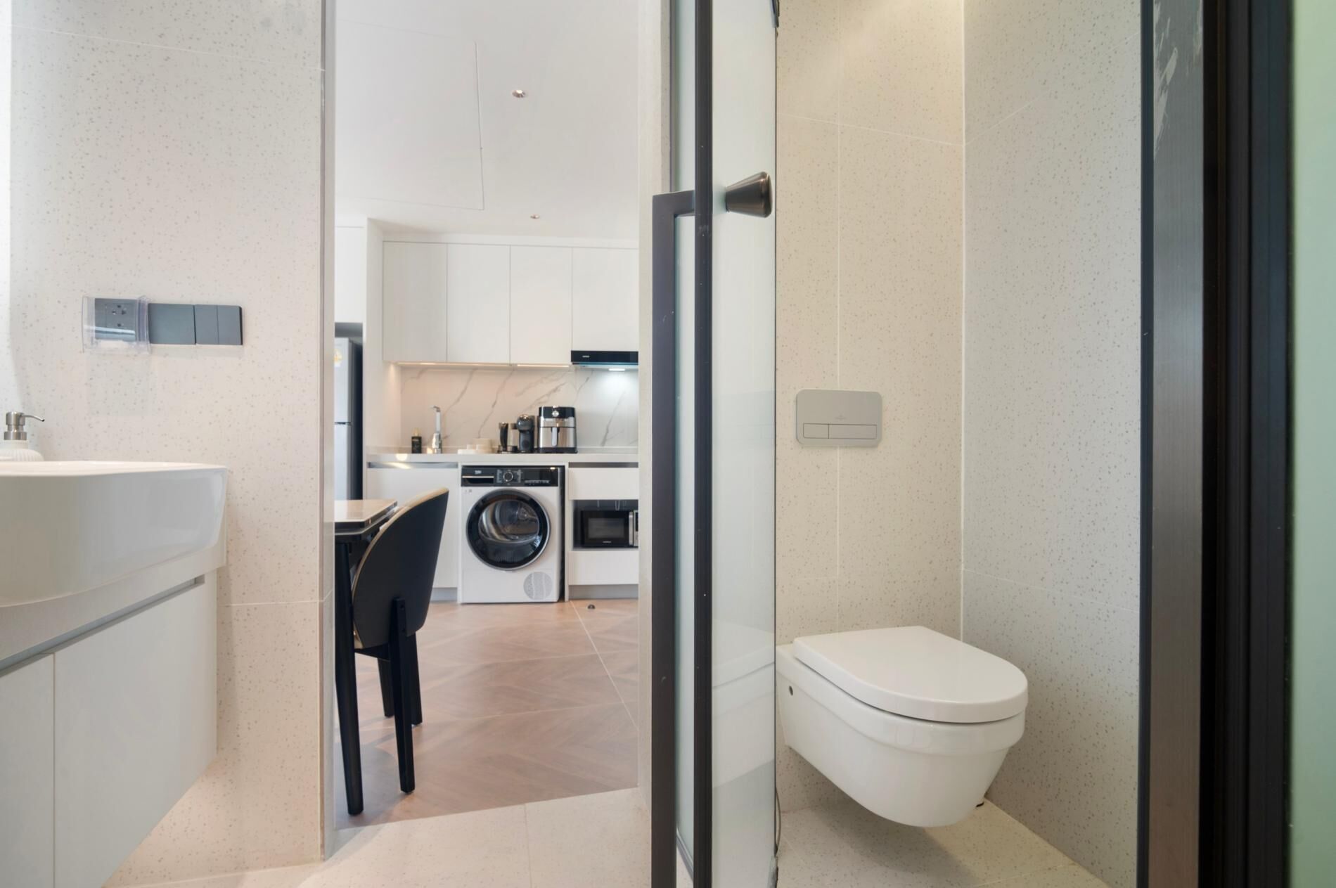 A compact kitchen with a washing machine, a sink, and a toilet.