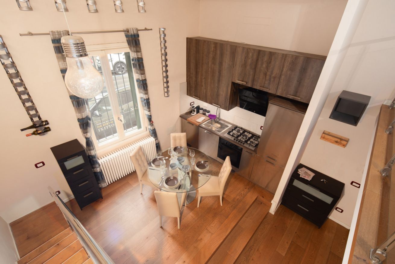 A compact kitchen with a dining table, wooden cabinets, and a built-in oven.