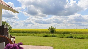 A patio with a brick floor, a wooden chair, and a vase with purple flowers. - Villa Kranich - High-quality vacation home in the middle of nature (Trent)