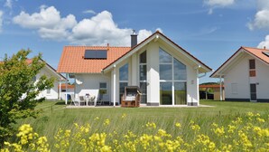 A modern house with a red-tiled roof, large windows, and a covered patio area. - Villa Kranich - High-quality vacation home in the middle of nature (Trent)