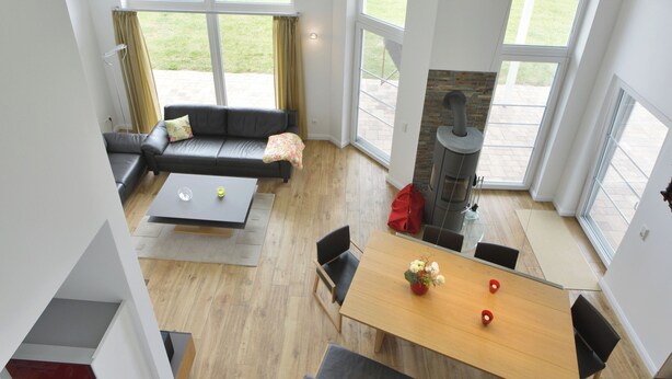 A modern interior with a dining area, a sofa, and a fireplace. - Villa Kranich - High-quality vacation home in the middle of nature (Trent)