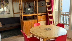 Una habitación con literas, un escritorio con computadora, una mesa redonda de madera con sillas y una ventana con vistas.