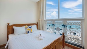 A bedroom with a large window, a wooden bed, and a balcony with decorative metal railings. - Oasky Vung Tau - AnNam Village (Ho Chi Minh City)
