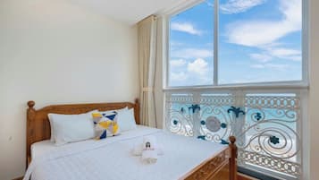 Quarto com uma janela grande, cama de madeira e varanda com grades de metal decorativas.