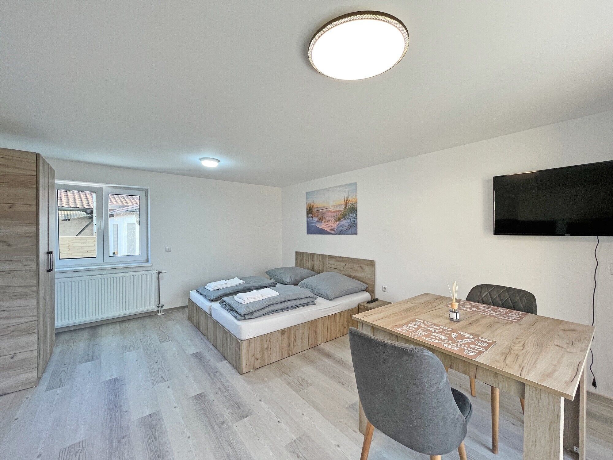 Une chambre à coucher moderne avec un lit, une table de chevet et un téléviseur fixé au mur.