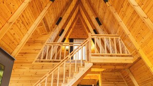 A wooden interior with a staircase leading to a loft area. - TİMİRA DAĞ EVLERİ (Dereli)