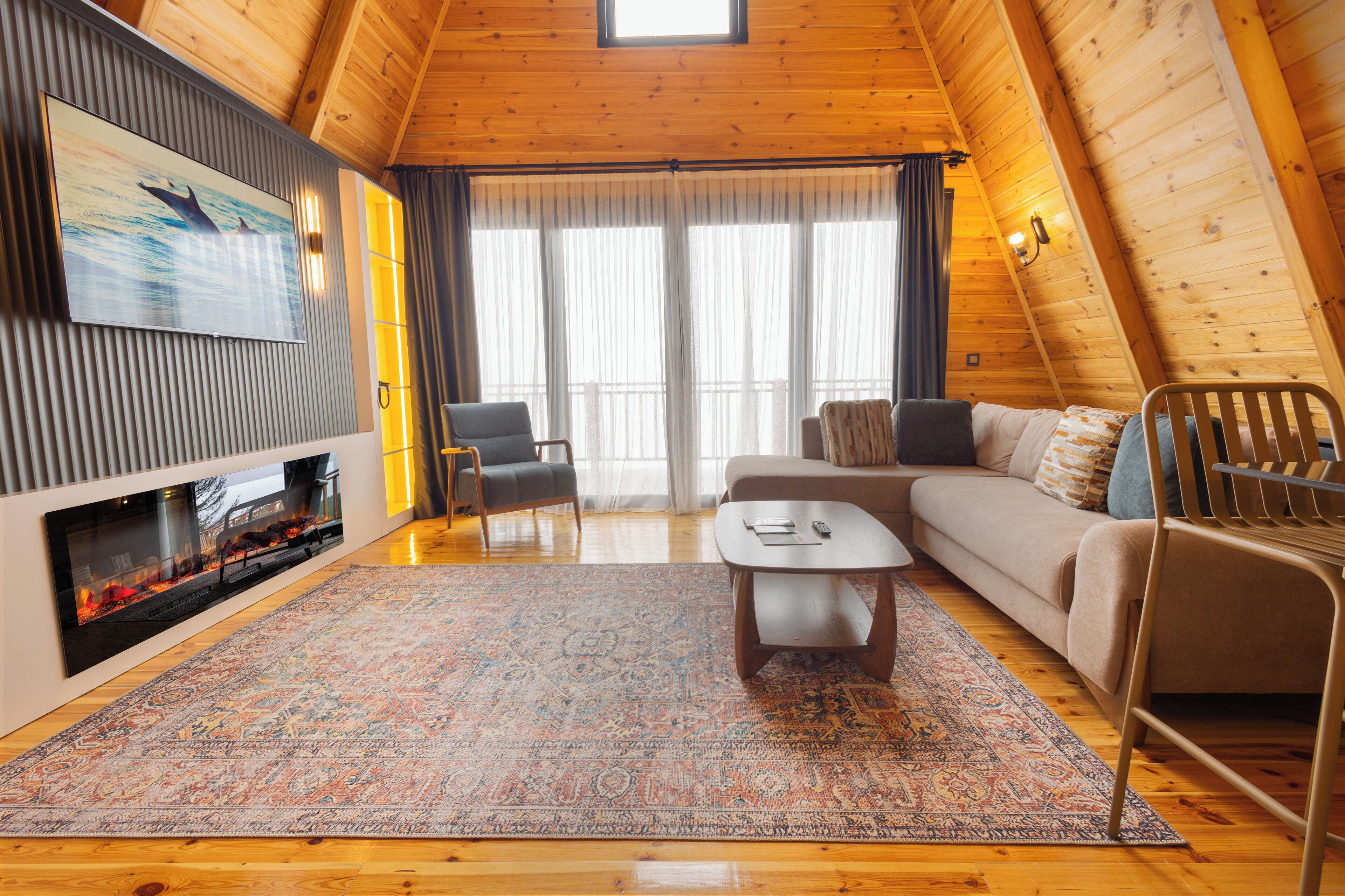 Una sala de estar acogedora con chimenea, un sofá, una mesa de centro y un televisor instalado en la pared.