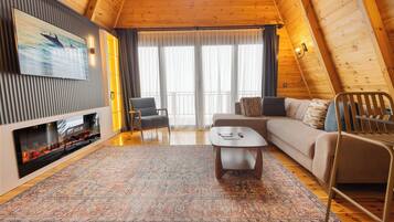 Una sala de estar acogedora con chimenea, un sofá, una mesa de centro y un televisor instalado en la pared.