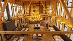 A wooden interior with a central chandelier, multiple windows, and a fireplace. - TİMİRA DAĞ EVLERİ (Dereli)
