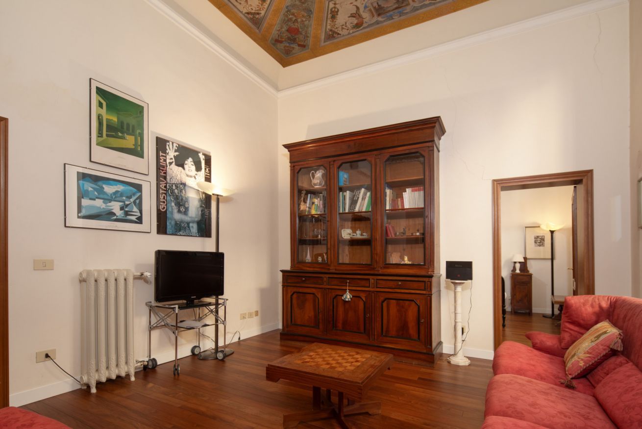 Een woonkamer met een houten kast, een televisie en een rode bank.