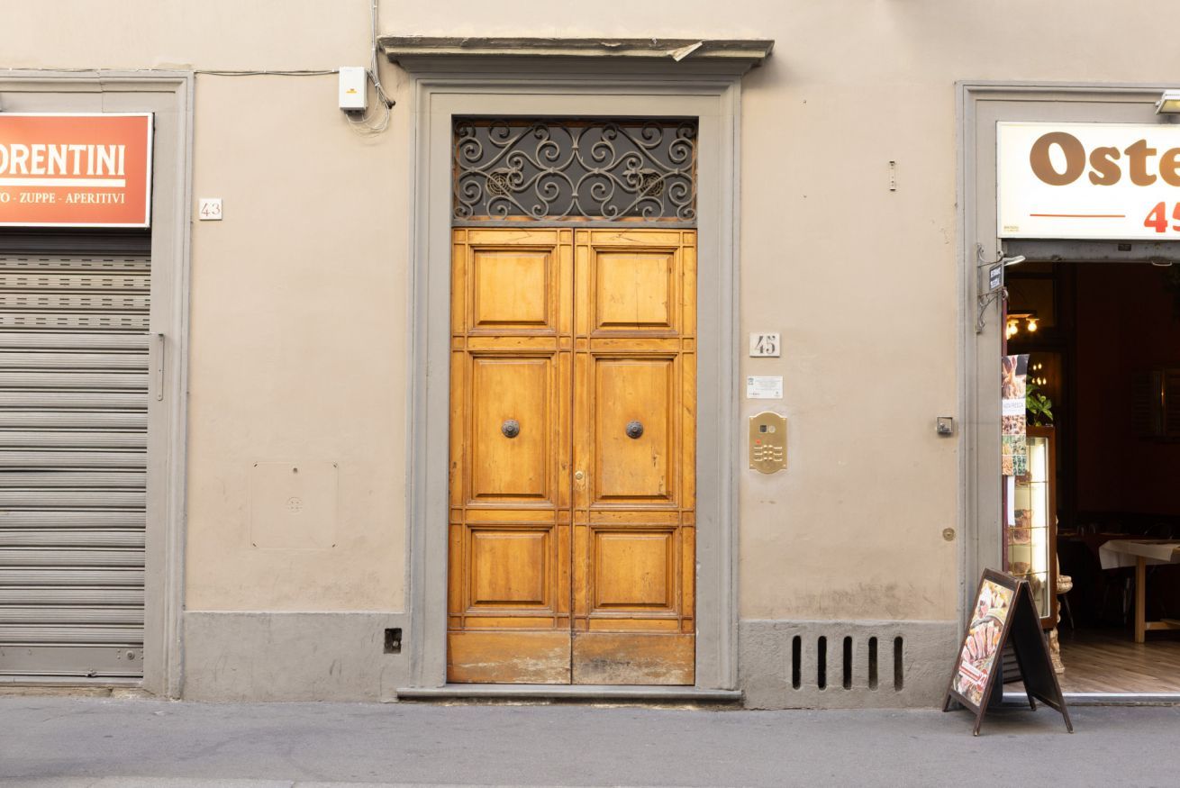 A wooden double door with a decorative metal top, flanked by closed shutters on either side.
