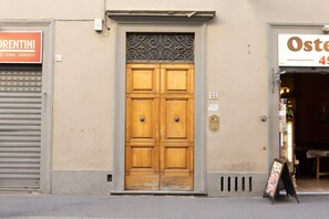 A wooden double door with a decorative metal top, flanked by closed shutters on either side. - Frescoed Duomo Retreat (Firenze)