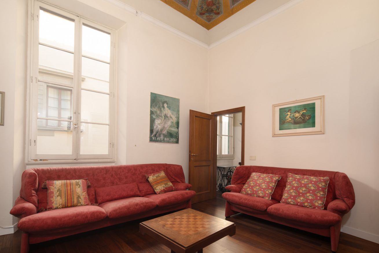 Una habitación con dos sofás rojos, una mesa de centro de madera y dos cuadros en las paredes.