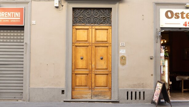 A wooden double door with a decorative metal top, flanked by closed shutters on either side. - Frescoed Duomo Retreat (Firenze)