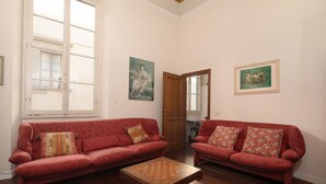 A room with two red sofas, a wooden coffee table, and two paintings on the walls. - Frescoed Duomo Retreat (Firenze)