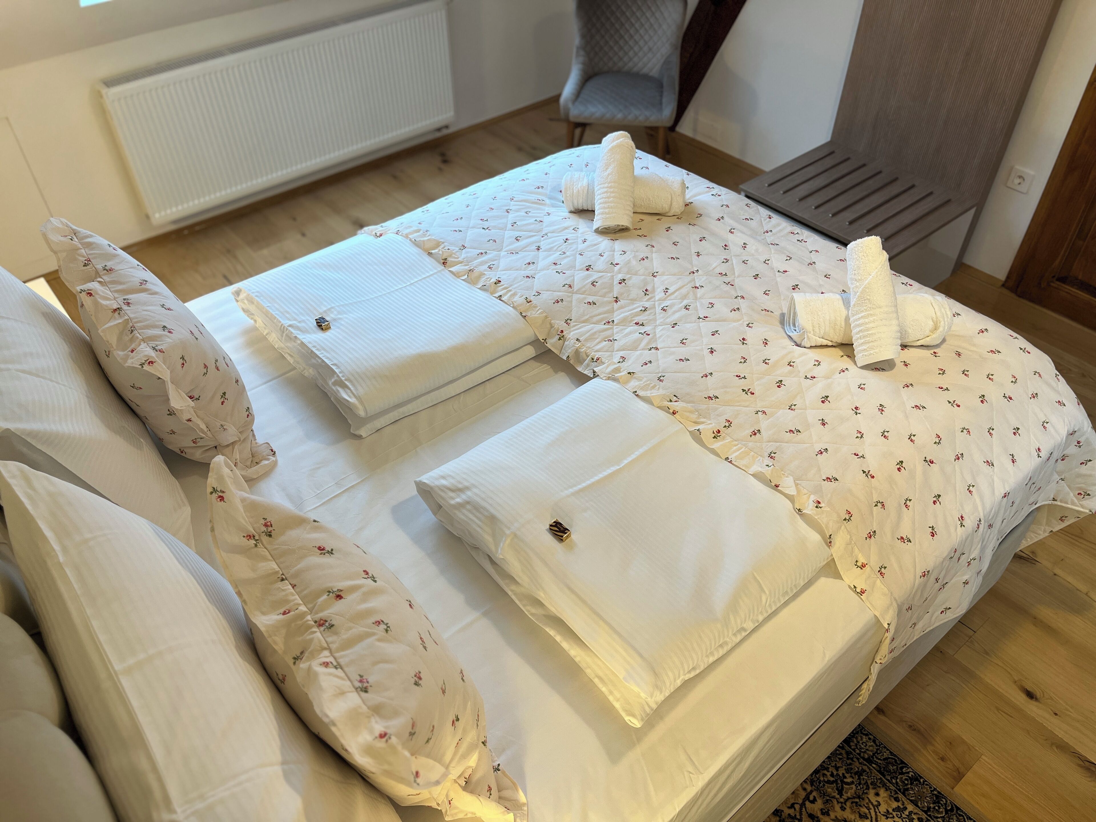A neatly made bed with floral-patterned bedding and multiple pillows.
