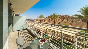 A balcony with a glass table, two chairs, and a plate of grapes and lemons. - Modern Eilat Escape by Sea N' Rent (Eilat)