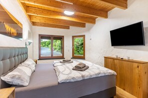 A bedroom with a bed, a television, and a wooden headboard.