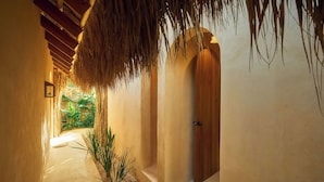 A narrow hallway with a thatched roof, a wooden door, and a framed picture on the wall. - 7 BEDROOM BUNGALOW WITH POOL & A/C, NEAR MACAO BEACH (Punta Cana)