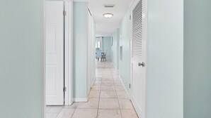 A hallway with white doors, a tiled floor, and a ceiling with a light fixture. - Ocean Villas Unit 118: Lagoon-Side Luxury with Direct Access (St. Augustine Beach)