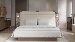 Ein modernes Schlafzimmer mit einem großen Bett, einem Holz-Kopfteil und einem Nachttisch mit Lampe.