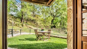 An outdoor patio with a table and chairs, surrounded by a stone wall and a metal fence. - Villa of approximately 150 m2 located on the ground floor and on two levels with air conditioning, independent heating and wi fi line.Composed of a large living room with independent equipped kitchen, fridge, microwave oven, toaster, sofa and satellite t (Sorano)