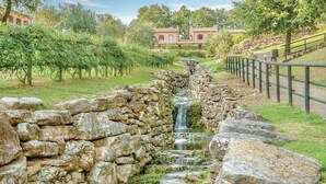 A stone-lined water channel with a waterfall, surrounded by lush greenery and a stone wall. - Villa of approximately 150 m2 located on the ground floor and on two levels with air conditioning, independent heating and wi fi line.Composed of a large living room with independent equipped kitchen, fridge, microwave oven, toaster, sofa and satellite t (Sorano)