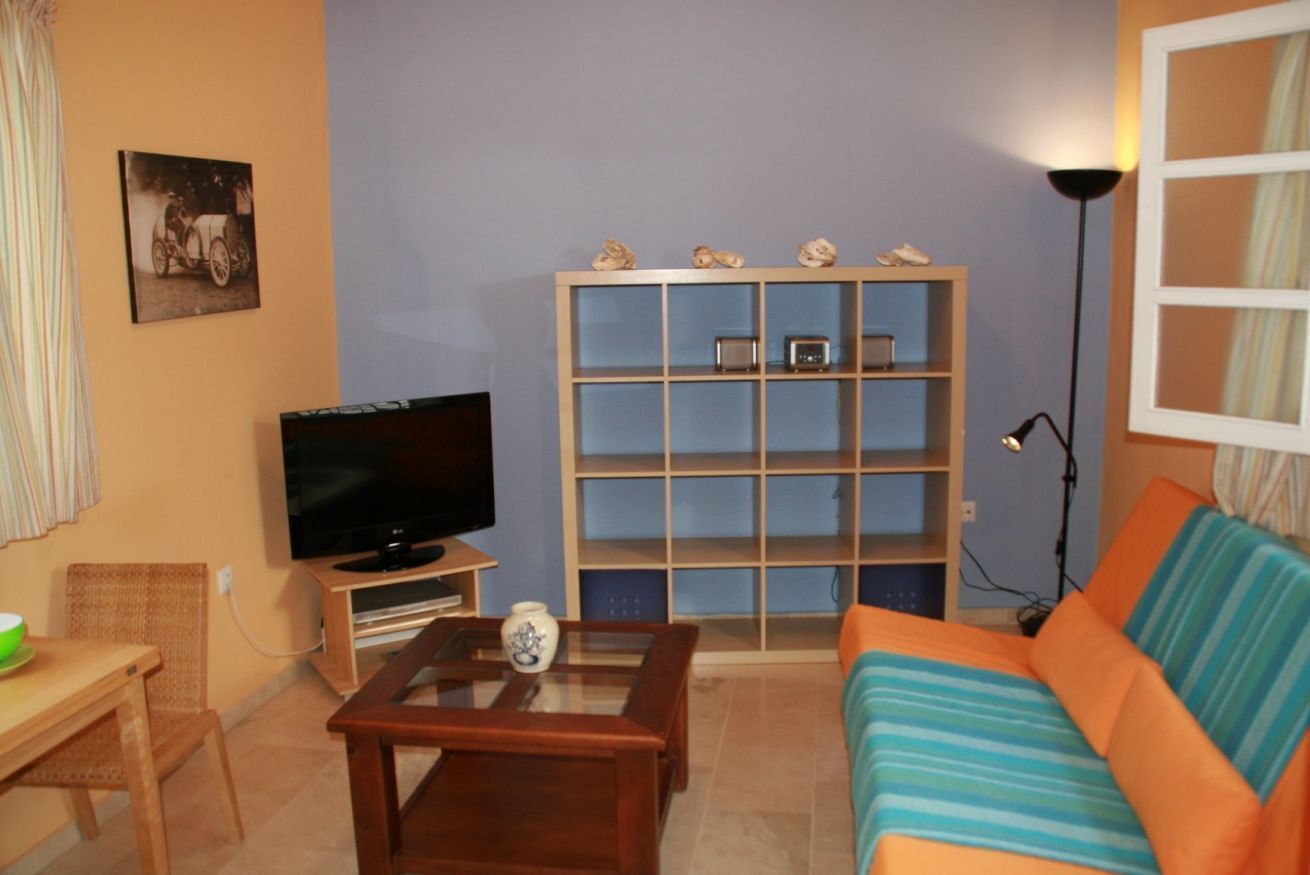 Een woonkamer met een televisie, een boekenkast, een bank en een salontafel.