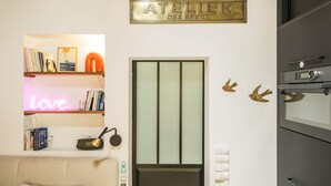 Eine Küche mit Einbauofen, einem an der Wand befestigten Schild mit der Aufschrift 'ATELIER DES RÈVES' und einem Bücherregal mit Büchern und Dekoration.