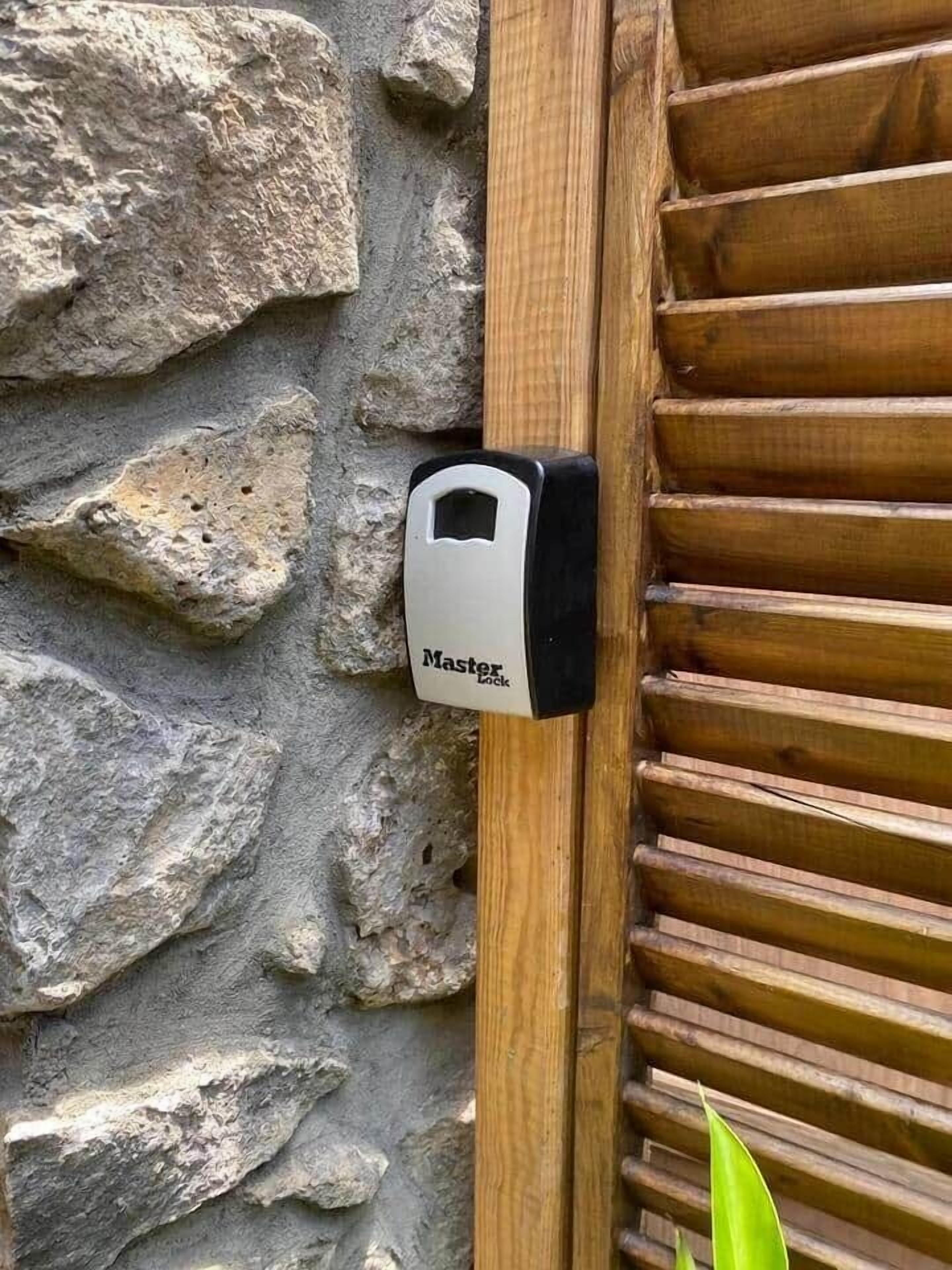 A Master Lock on a stone wall next to a wooden door.