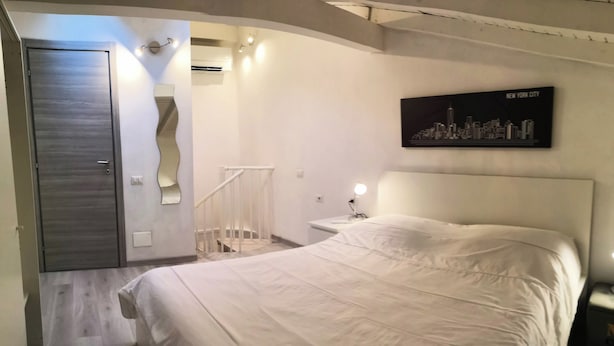 Ein Schlafzimmer mit einem Bett, einem Stadtbild als Kunstwerk, einer Tür und einer Treppe.