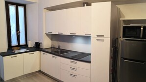 Eine moderne Küche mit weißen Schränken, einer schwarzen Arbeitsplatte und einem Edelstahl-Kühlschrank.