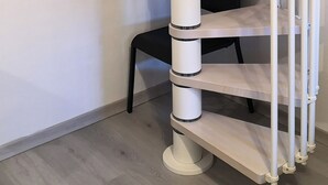 Eine Wendeltreppe mit weißen Geländern und einer zentralen Säule.