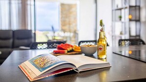 A book open on a table with a bottle and a bowl of fruit in the background. - Luxury sea-view apartment with terrace - Coral Estate (Sint Willibrordus)