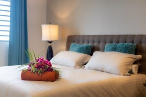 A neatly made bed with a floral arrangement, a lamp, and two pillows on a headboard. - Luxury apartment with panoramic sea views (Sint Willibrordus)