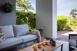 A modern outdoor seating area with a sofa, a table with breakfast items, and a view of lush greenery. - Luxury ground-floor retreat with poolside terrace (Sint Willibrordus)