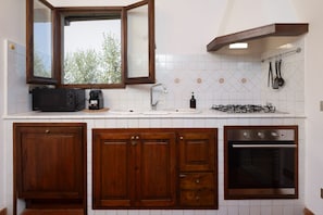 A kitchen with wooden cabinets, a built-in oven, a microwave, and a gas stove. - La Dolce Vita in Settignano (Firenze)