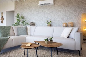 A modern living room with a sofa, two wooden coffee tables, and decorative plants. - Luxury penthouse with panoramic sea views (Sint Willibrordus)