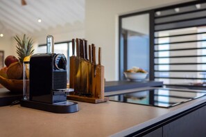 A kitchen counter with a coffee maker, a knife block, and a bowl of fruit. - Luxury penthouse with panoramic sea views (Sint Willibrordus)