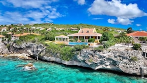 Una propiedad costera con una casa grande, piscina y costa rocosa.