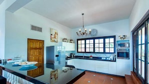 Una cocina moderna con una isla central, una araña y un ventanal grande.