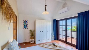 Un dormitorio con cama, armario, ventilador y vistas a través de un gran ventanal.
