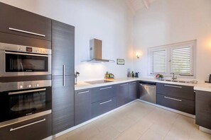 Una cocina moderna con electrodomésticos integrados, armarios grises y una ventana con persianas.