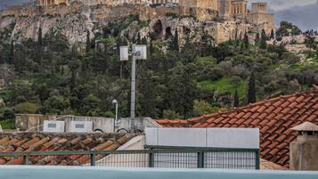 A view of ancient ruins atop a hill with modern buildings in the foreground.