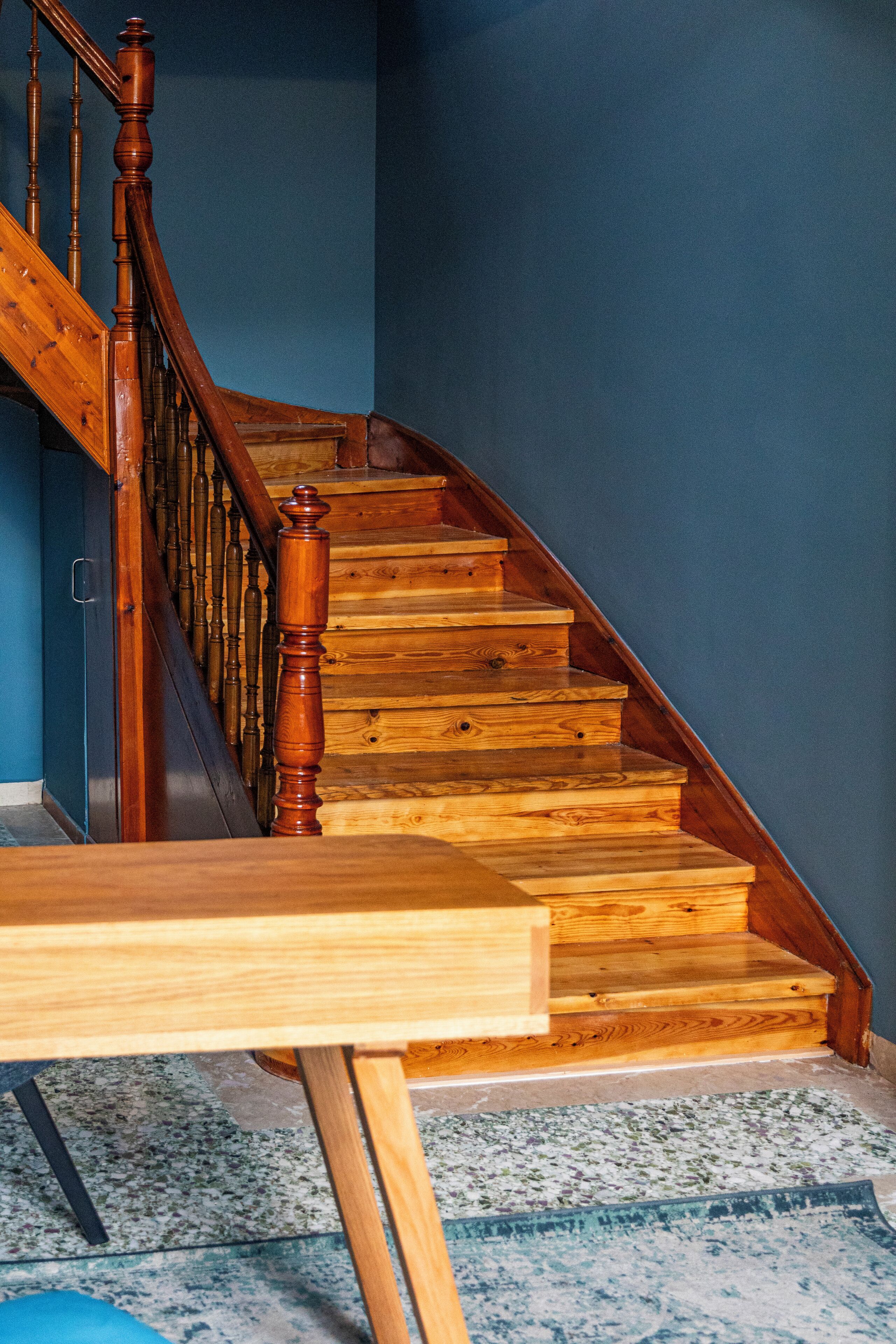 Una escalera de madera con barandilla y piso alfombrado.